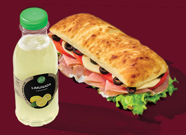 Na slici su boca limunade z brandom Petrol in pečeno pecivo z nadevom, položeni na temno rdečem ozadju.