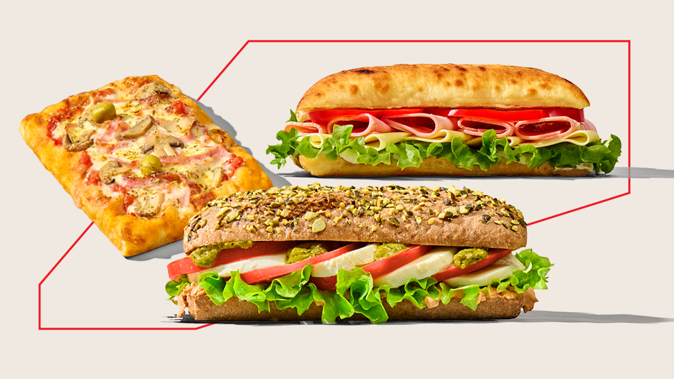 Na slici su svježi sendviči i focaccia s povrćem, sirom, mesnim narescima i salatom na svijetloj podlozi.