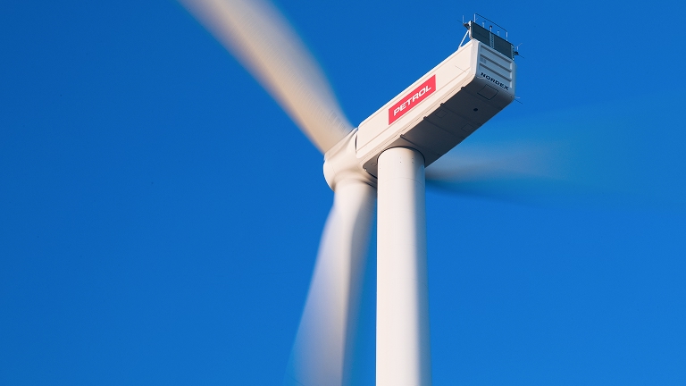 Vjetroturbina s Petrolovim logotipom proizvodi energiju pod vedrim plavim nebom.